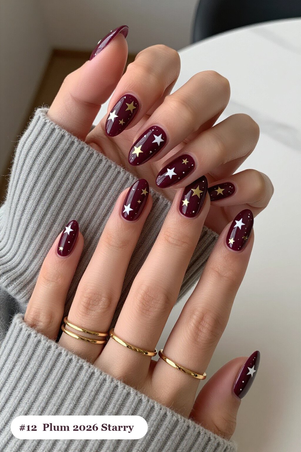 Medium almond deep plum 2026 nails with white and gold stars and sparkles painted on every nail, perfect for autumn - autumn nails 2026