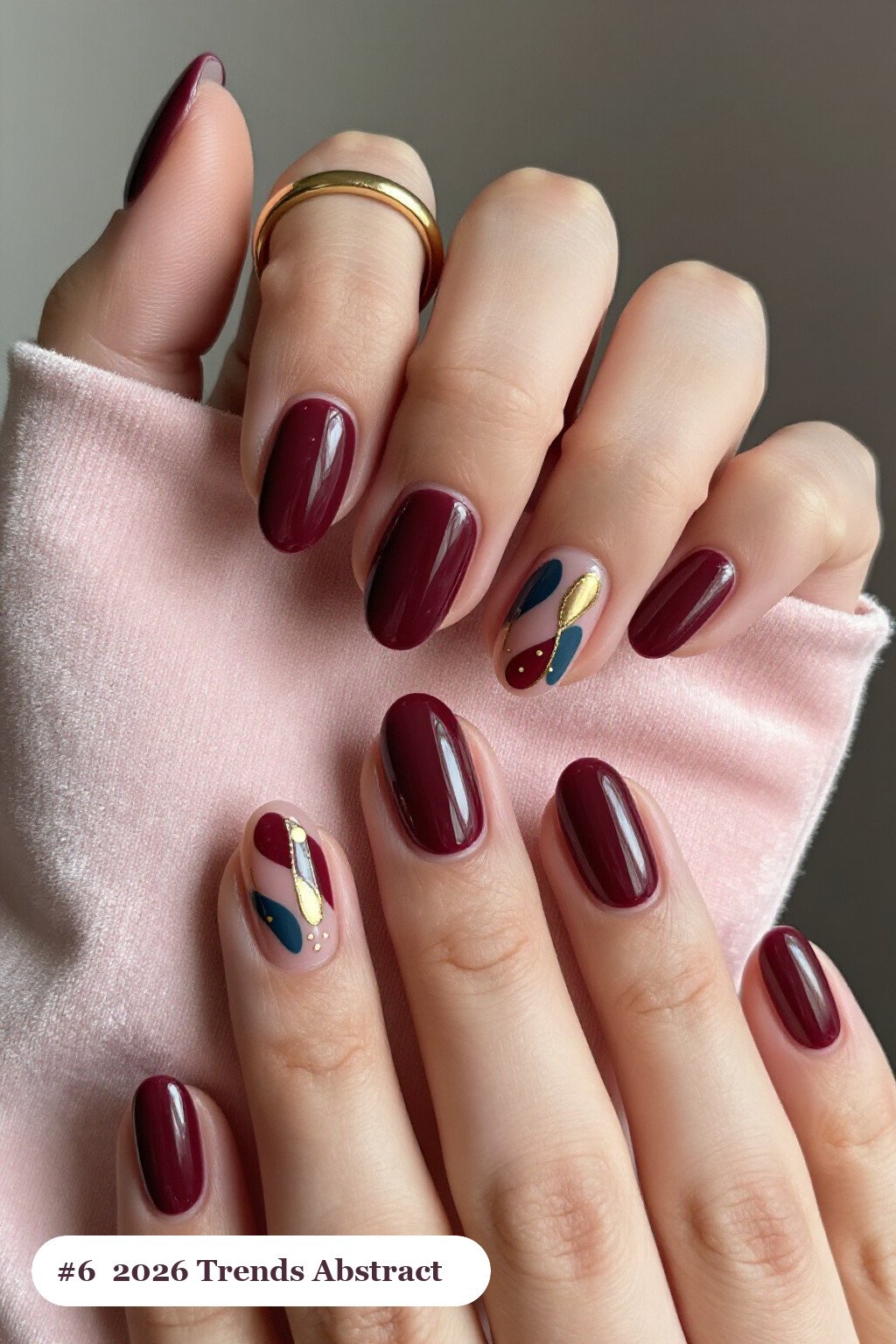 Medium oval burgundy 2026 trends nails with abstract art of colour blobs, gold outlines and dots, perfect for christmas - christmas nails 2026 trends