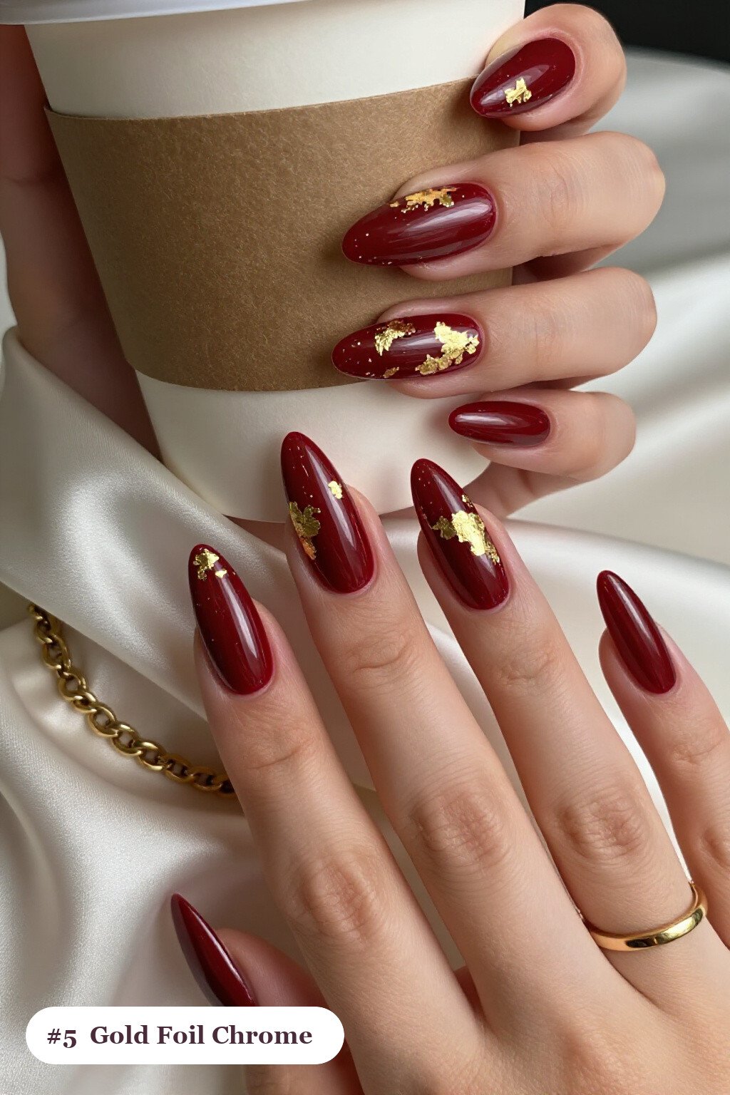 Long stiletto cherry red coffee chrome nails with a liquid chrome mirror finish clearly visible on every nail, styled with dense gold foil flakes and gold leaf scattered across every nail - coffee chrome nails