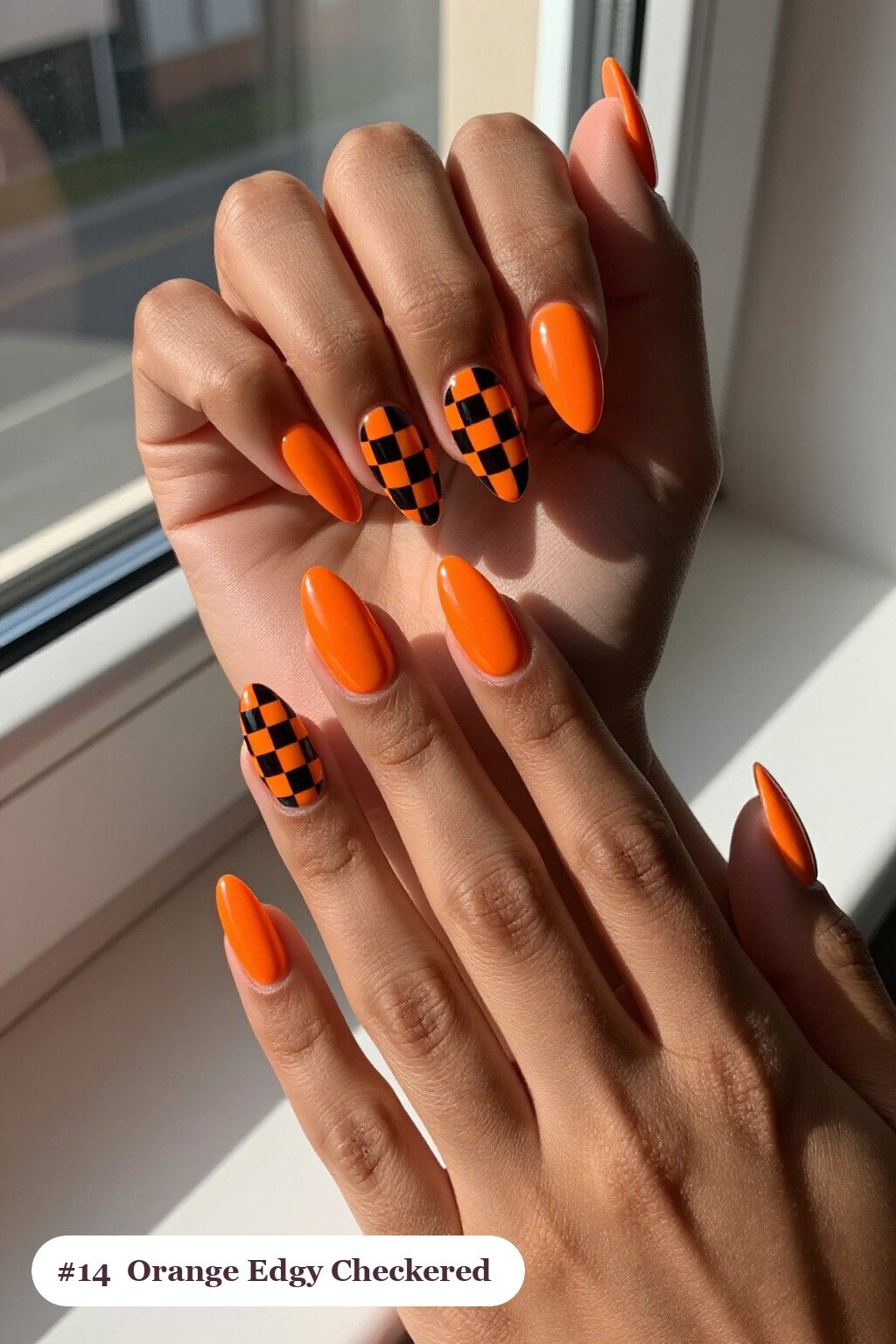 Medium Almond Orange Nails with Bold Checkerboard Accents and Solid Base - edgy halloween nail ideas