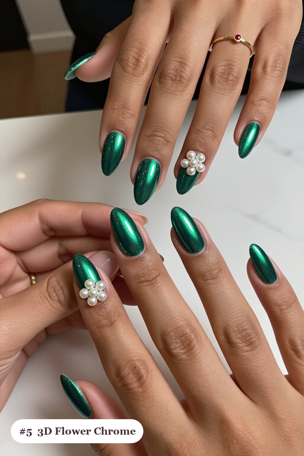 Medium almond emerald chrome nails with a liquid chrome mirror finish clearly visible on every nail, styled with raised 3D flowers with pearl centres on two accent nails, with pearl details - emerald chrome almond nails