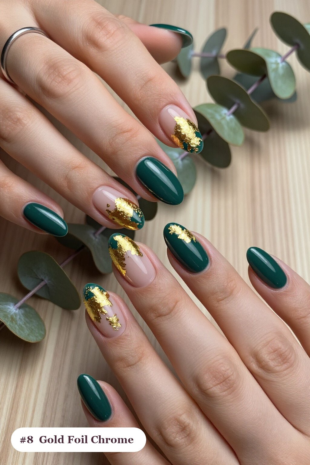 Medium almond emerald chrome nails with a liquid chrome mirror finish clearly visible on every nail, styled with dense gold foil flakes and gold leaf scattered across every nail, with soft nude details - emerald chrome almond nails
