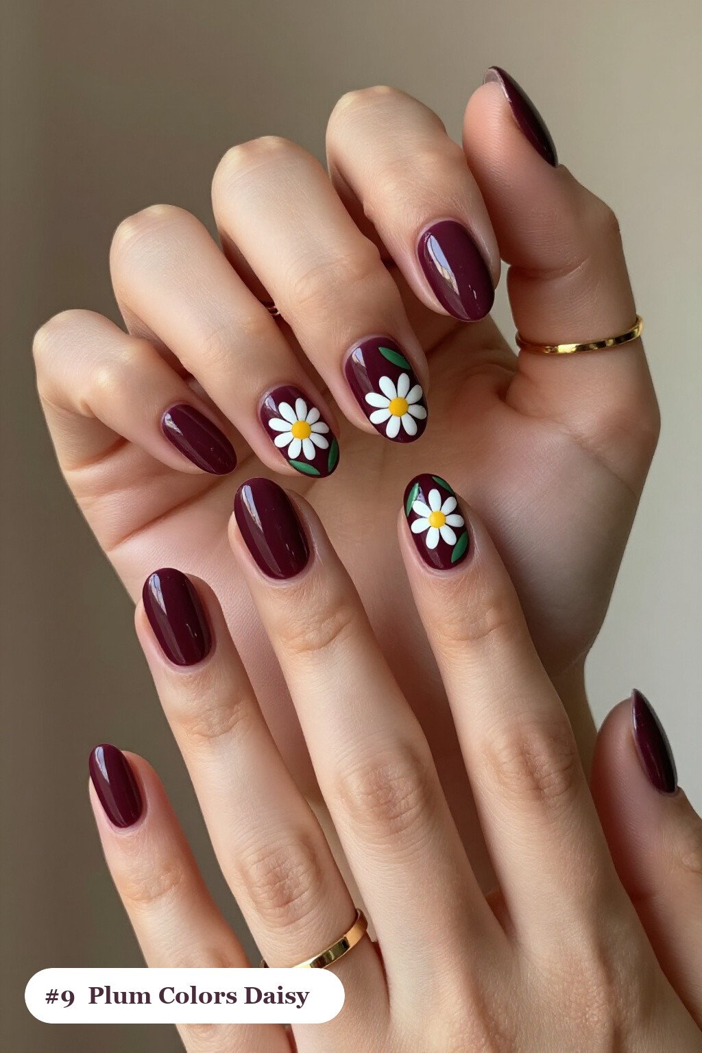 Medium oval deep plum colors nails with hand-painted daisies and green leaves across every nail, perfect for fall - fall nail colors