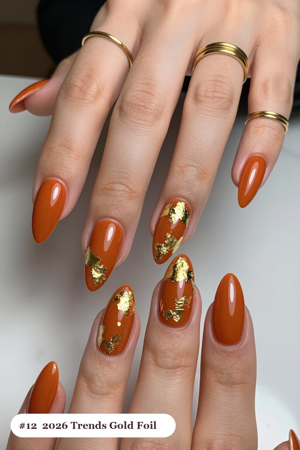 Burnt Orange Stiletto Nails Covered in Dense Gold Foil Flakes and Gold Leaf - fall nails 2026 trends