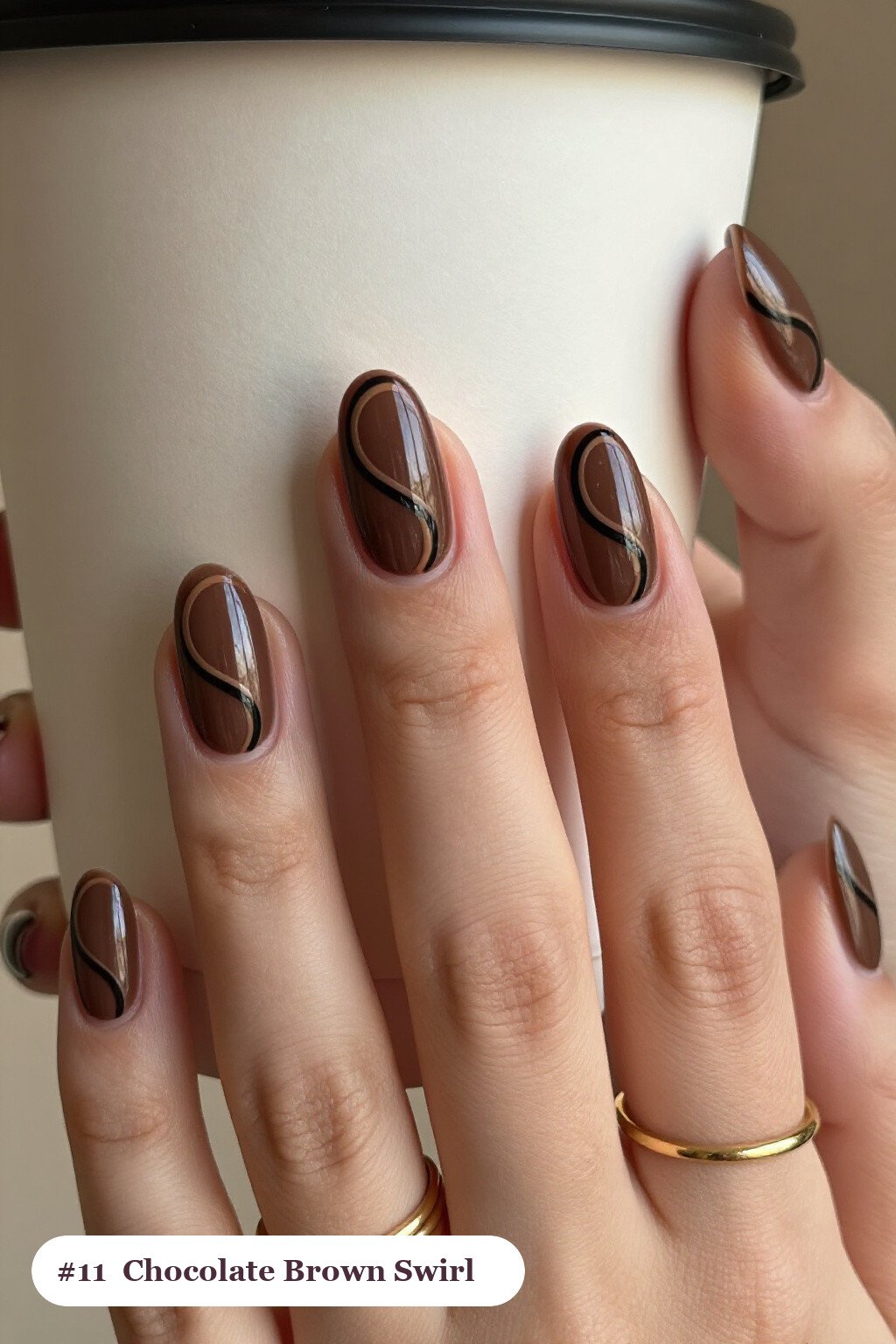 Short almond chocolate brown nails with bold hand-painted swirl lines flowing across every nail in a contrasting colour, perfect for fall - fall nails short