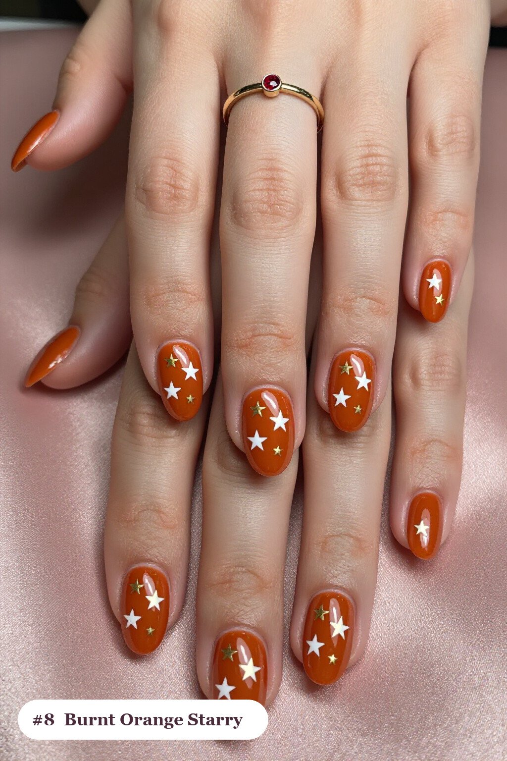 Short almond burnt orange nails with white and gold stars and sparkles painted on every nail, perfect for fall - fall nails short
