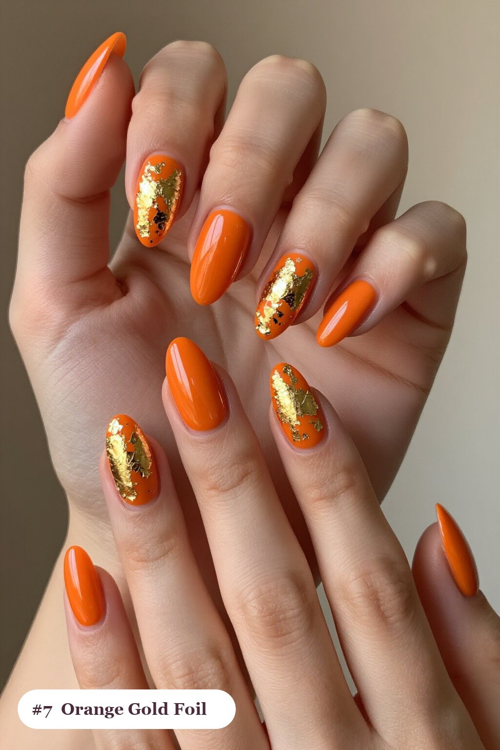 Medium almond orange nails with dense gold foil flakes and gold leaf scattered across every nail, perfect for halloween - halloween almond nails