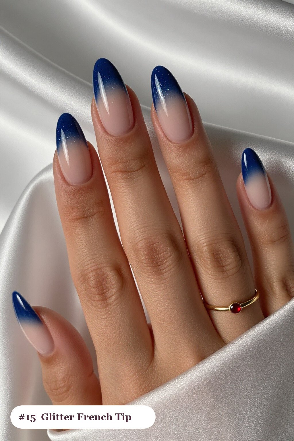 Medium almond navy blue ombre french nails with crisp french tips and a smooth ombre gradient clearly visible on every nail, styled with a sparkling glitter gradient rising from the cuticle - ombre french almond nails