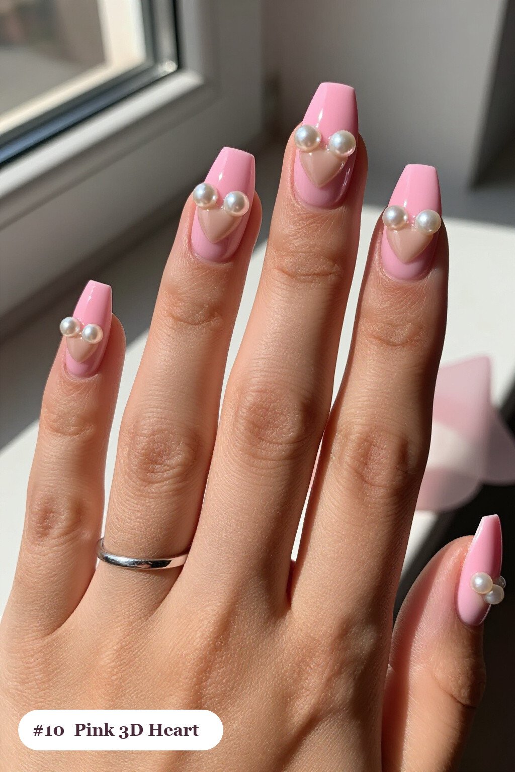 Medium square pink nails with chunky 3D gel hearts and pearls on three nails, with soft nude details - pink nails Medium square pink nails with chunky 3D gel hearts and pearls on three nails, with soft nude details - pink nails