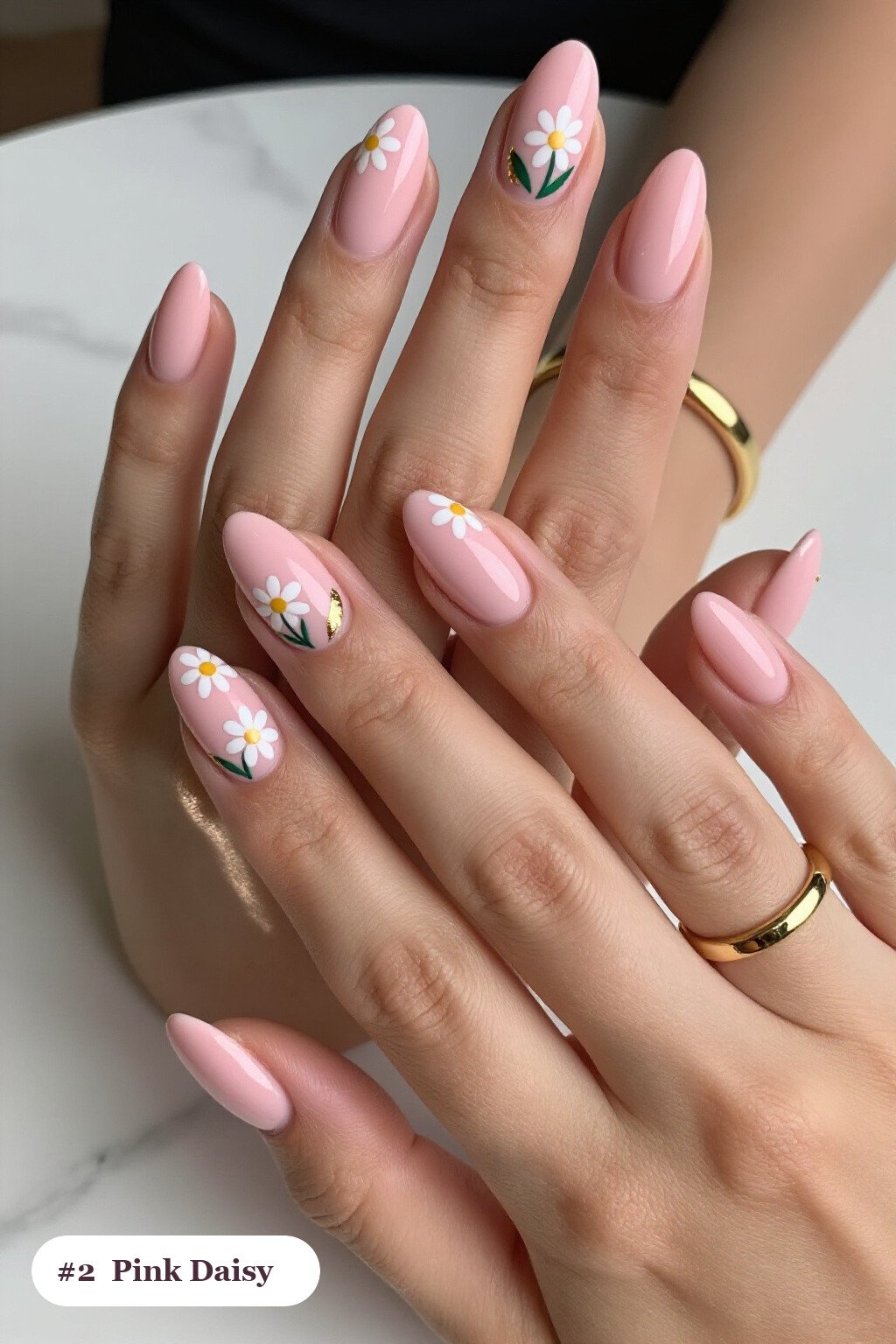 Medium almond pink nails with hand-painted daisies and green leaves across every nail, with gold details - pink nails almond