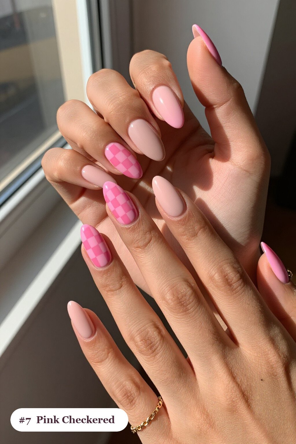 Medium almond pink nails with a bold checkerboard pattern on two accent nails and solid colour on the rest, with soft nude details - pink nails almond