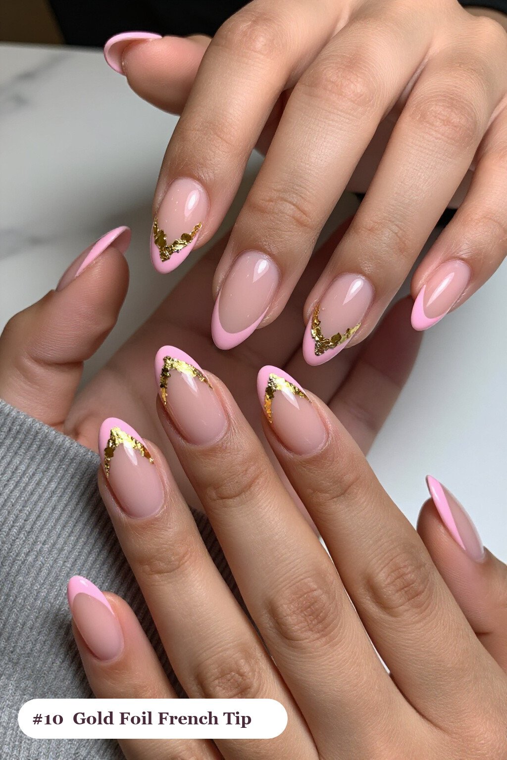 Medium almond pink french tip nails with crisp french tips clearly visible on every nail, styled with dense gold foil flakes and gold leaf scattered across every nail, with silver details - pink nails almond french tip