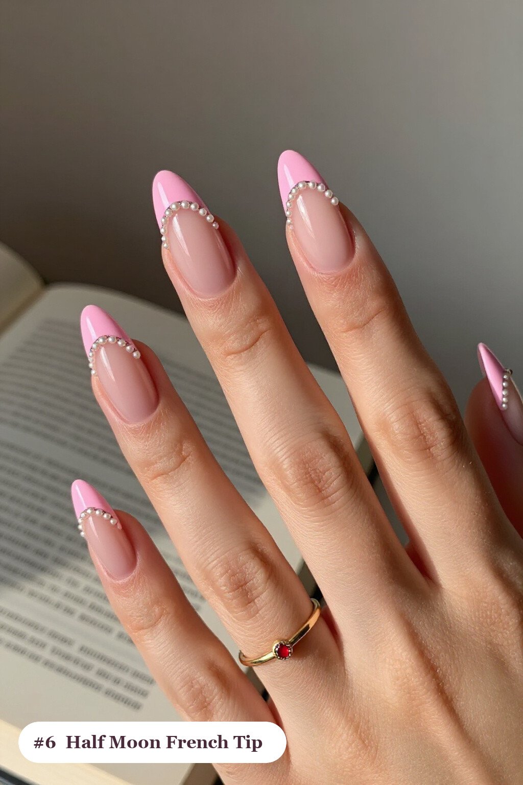 Medium almond pink french tip nails with crisp french tips clearly visible on every nail, styled with a half-moon design with a glitter crescent at the cuticle, with pearl details - pink nails almond french tip