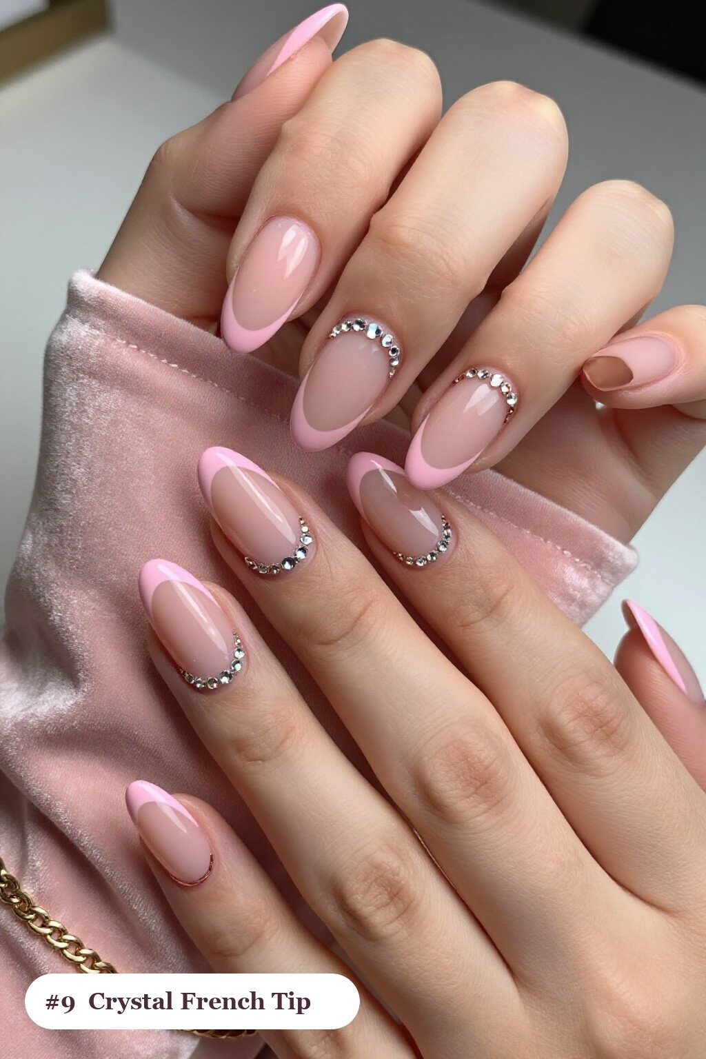 Medium almond pink french tip nails with crisp french tips clearly visible on every nail, styled with rows of sparkling crystal rhinestones along the cuticle of every nail, with rose gold details - pink nails almond french tip