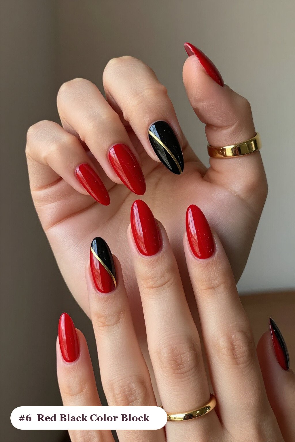 Long stiletto red black nails in a colour-block design split diagonally with a thin gold line, with gold details - red and black nails
