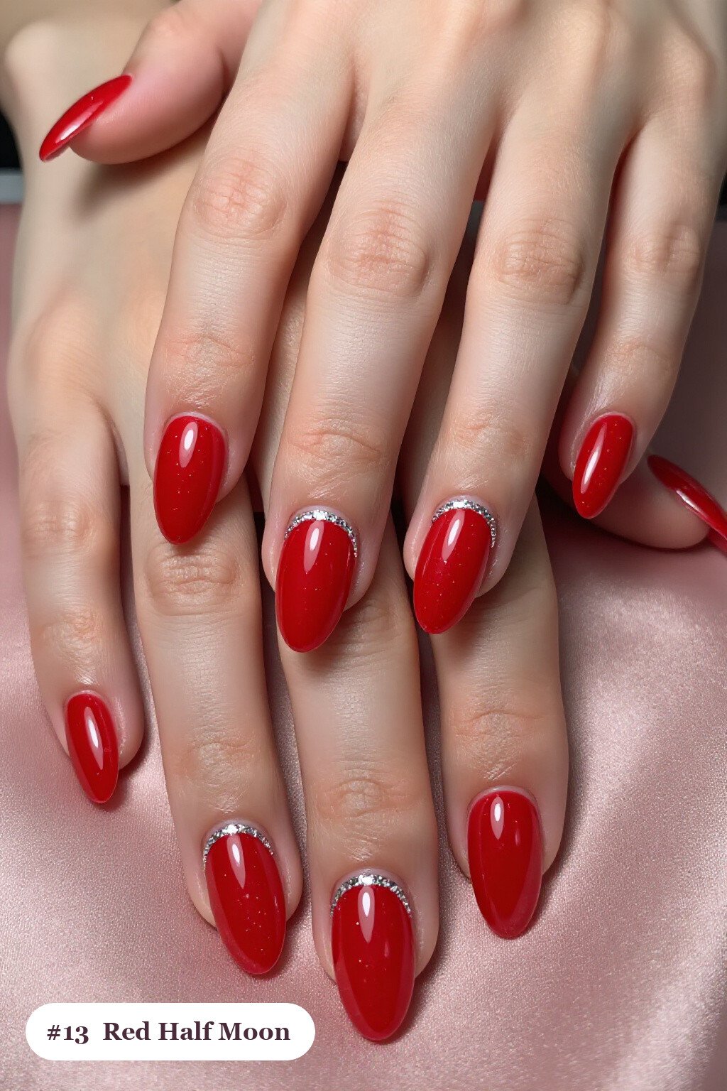 Medium almond red nails in a half-moon design with a glitter crescent at the cuticle, with silver details - red nails