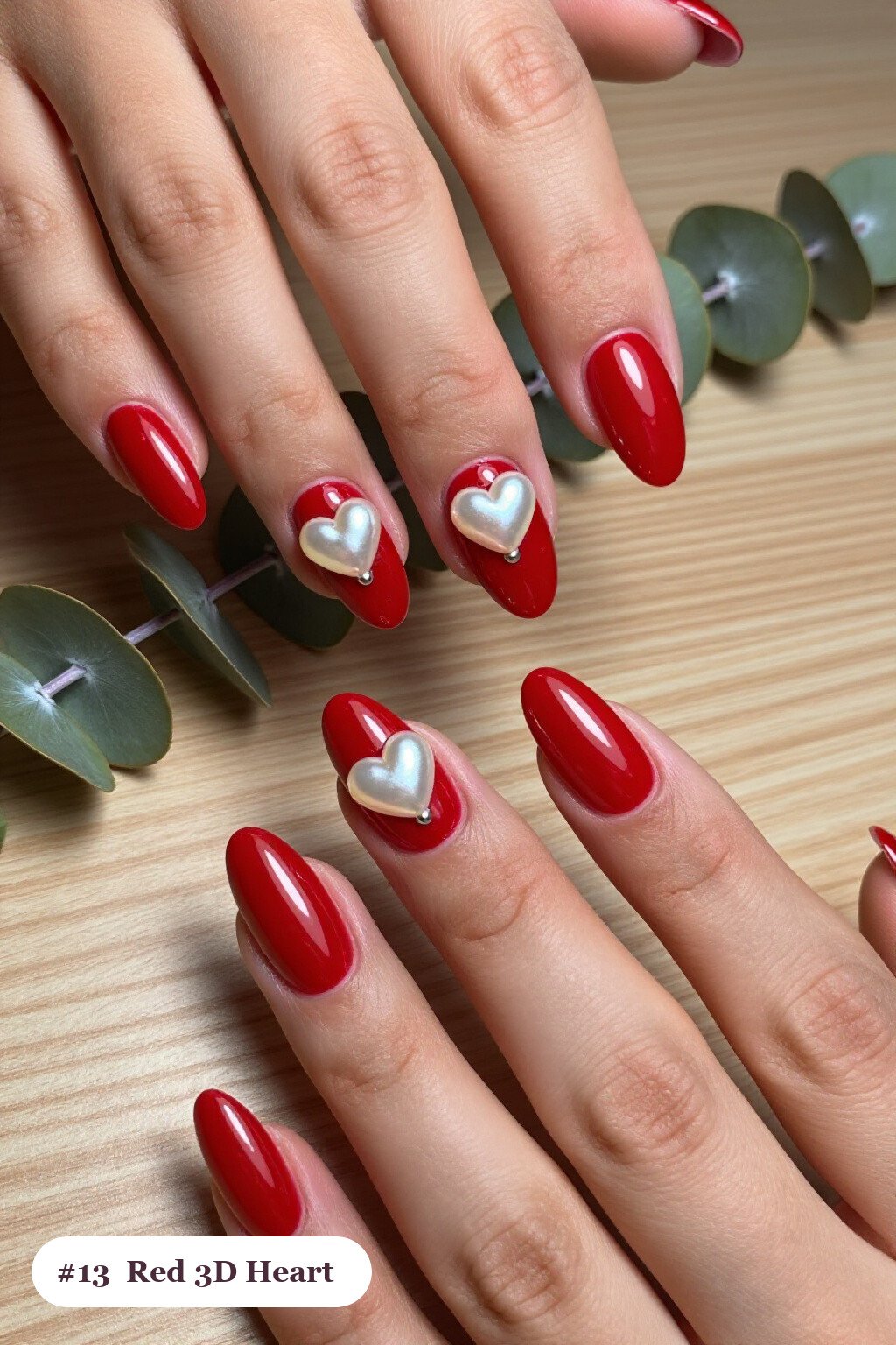 Medium almond red nails with chunky 3D gel hearts and pearls on three nails, with silver details - red nails almond