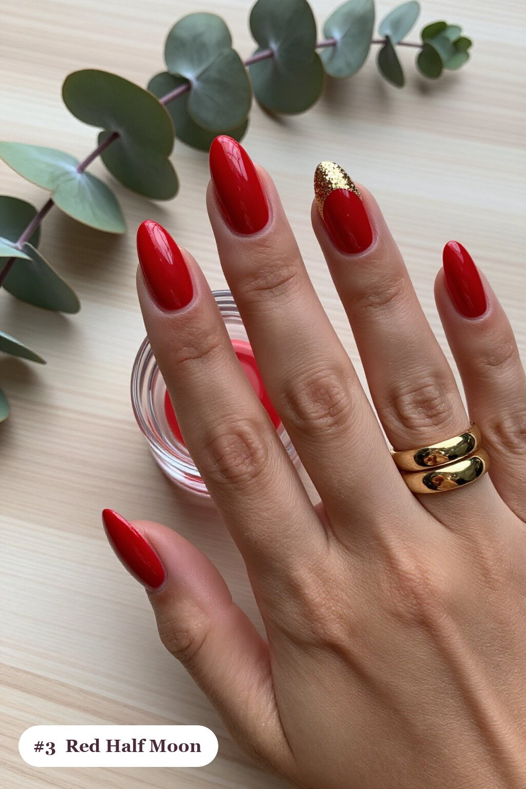 Medium almond red nails in a half-moon design with a glitter crescent at the cuticle, with gold details - red nails almond
