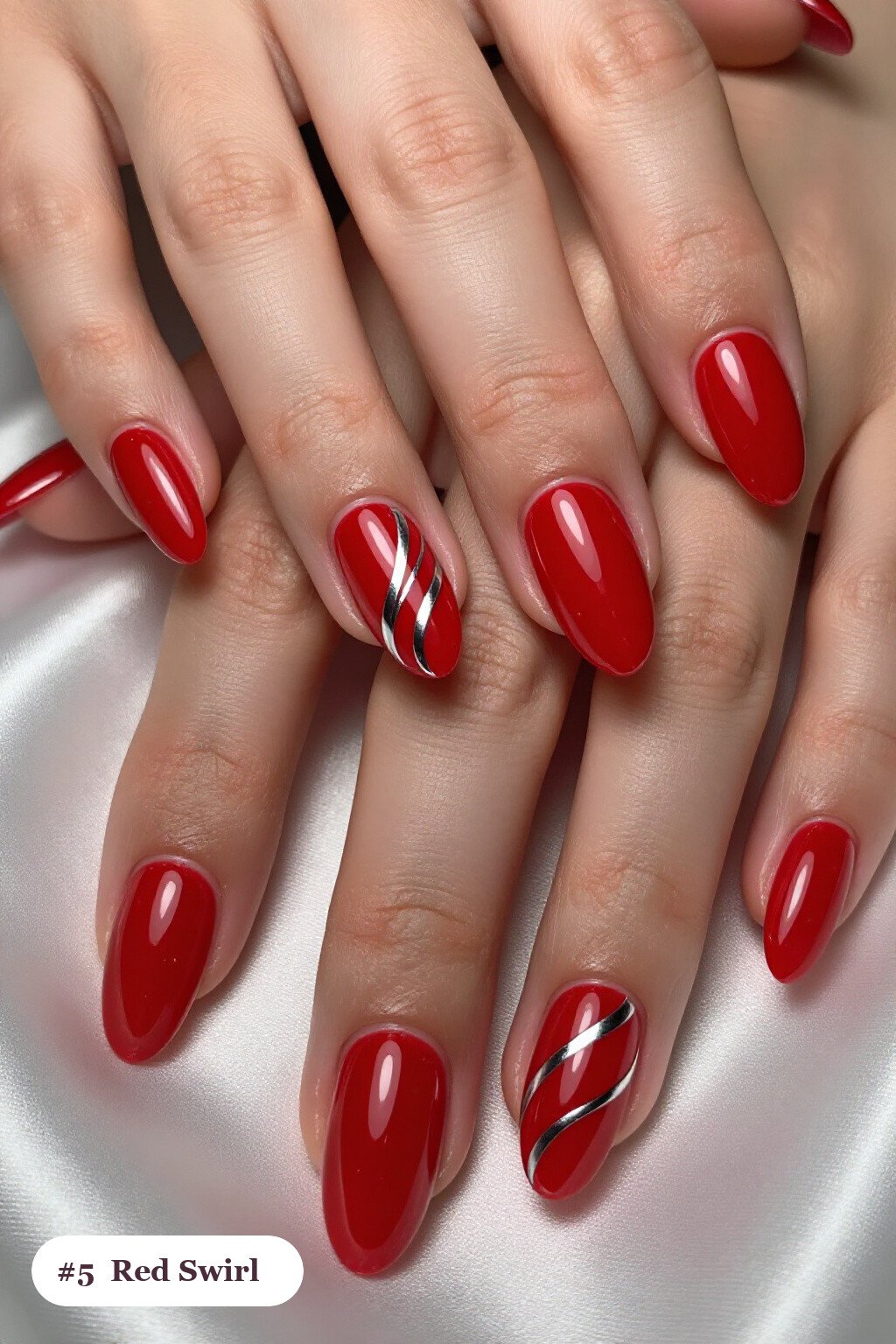 Medium almond red nails with bold hand-painted swirl lines flowing across every nail in a contrasting colour, with silver details - red nails almond