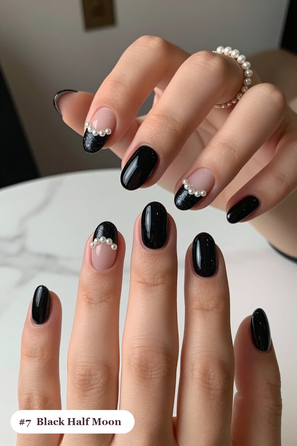 Short almond black nails in a half-moon design with a glitter crescent at the cuticle, with pearl details, perfect for halloween - short halloween nails black Short almond black nails in a half-moon design with a glitter crescent at the cuticle, with pearl details, perfect for halloween - short halloween nails black