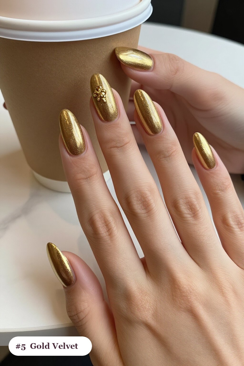 Long coffin gold nails in a velvet shimmer finish with one glossy accent nail with a gold charm, perfect for christmas - simple christmas nails Long coffin gold nails in a velvet shimmer finish with one glossy accent nail with a gold charm, perfect for christmas - simple christmas nails