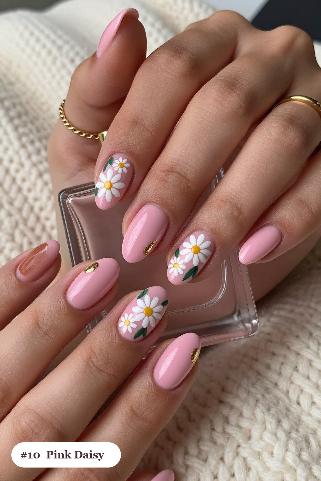 Medium oval pink nails with hand-painted daisies and green leaves across every nail, with gold details - simple pink nails