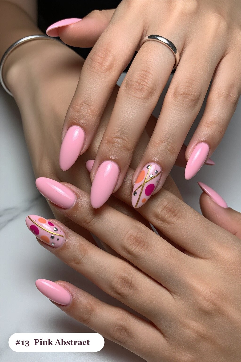 Long almond pink nails with abstract art of colour blobs, gold outlines and dots, with silver chrome details - simple pink nails