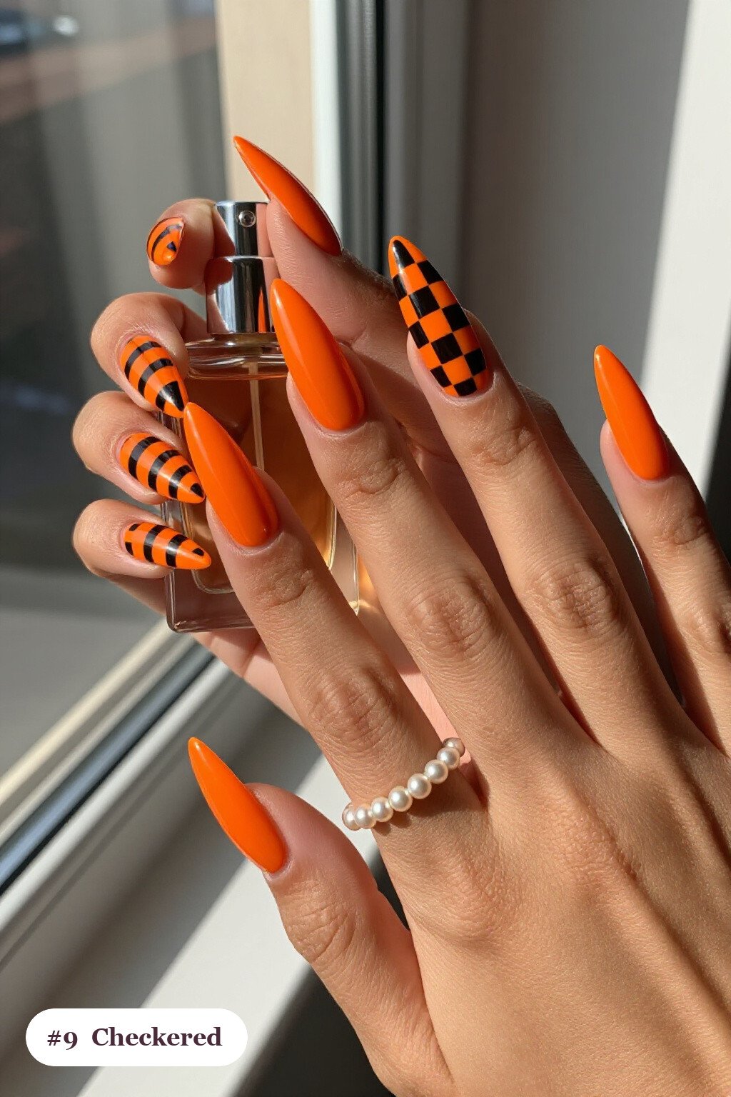 Orange Long Stiletto Nails with Bold Checkerboard Accent Pairings - spooky halloween nails