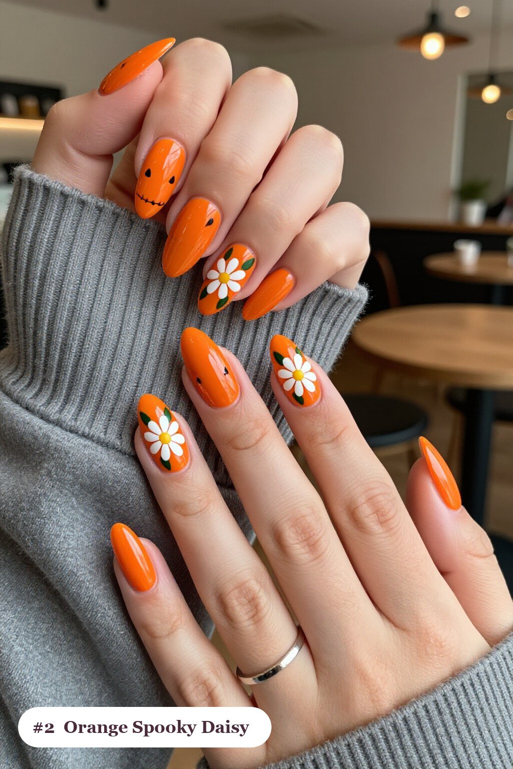 Medium almond orange spooky nails with hand-painted daisies and green leaves across every nail, perfect for halloween - spooky halloween nails almond