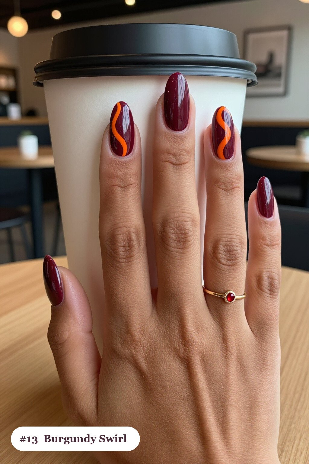 Medium almond burgundy nails with bold hand-painted swirl lines flowing across every nail in a contrasting colour, thanksgiving style - thanksgiving acrylic nail ideas