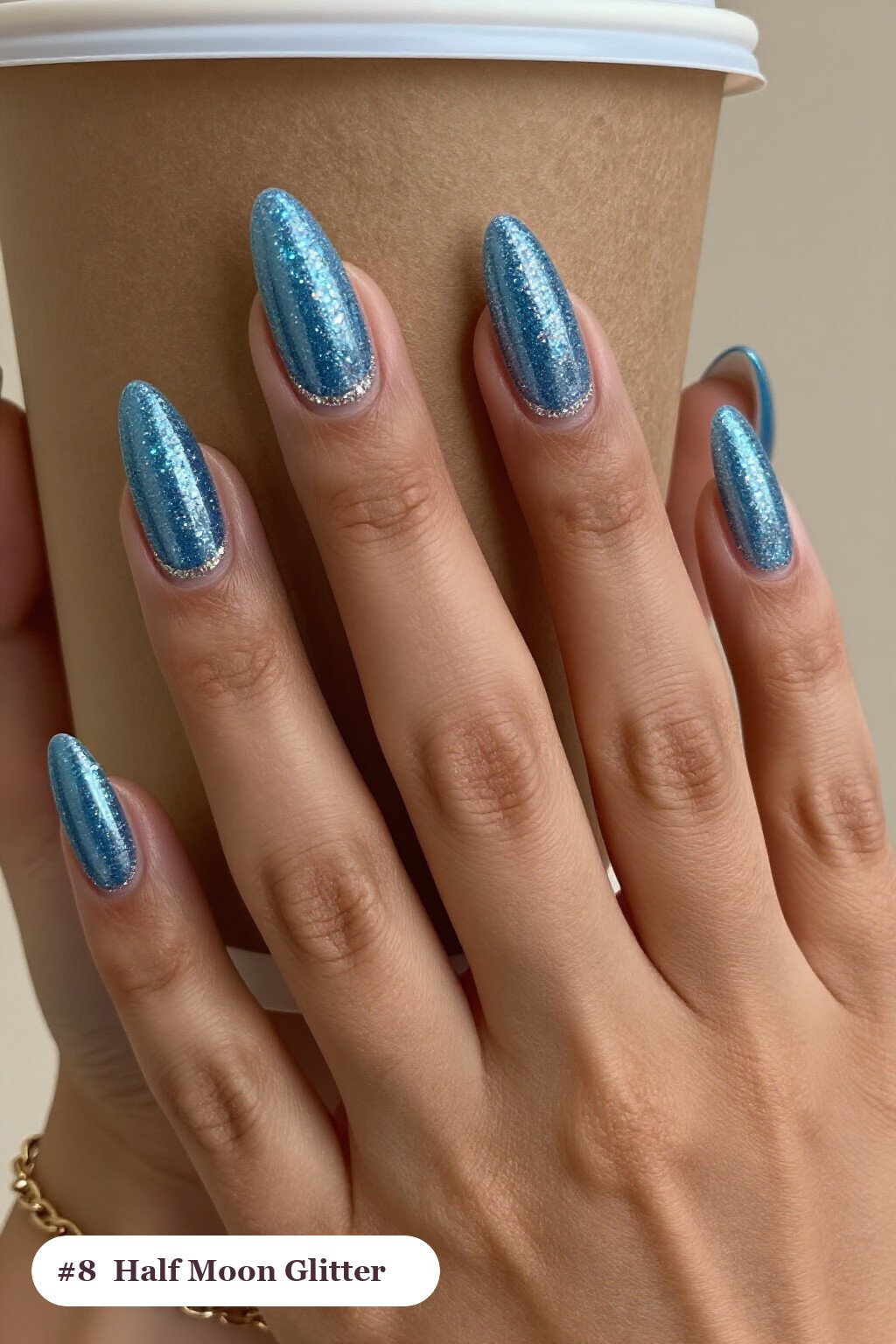 Medium almond icy blue glitter nails with sparkling glitter clearly visible on every nail, styled with a half-moon design with a glitter crescent at the cuticle, perfect for winter - winter glitter nails