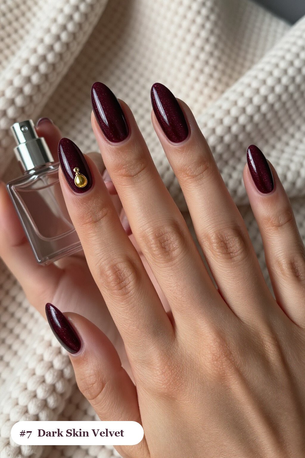 Medium almond plum dark skin nails in a velvet shimmer finish with one glossy accent nail with a gold charm, perfect for winter - winter nails for dark skin