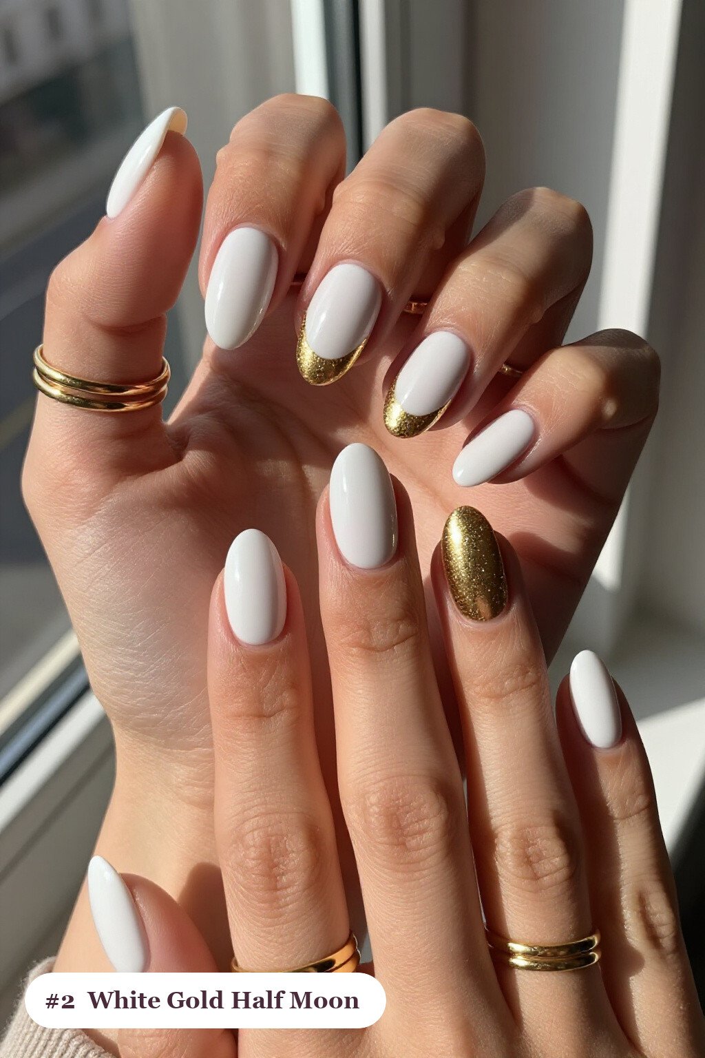 Medium oval white gold nails in a half-moon design with a glitter crescent at the cuticle, perfect for winter - winter white and gold nails