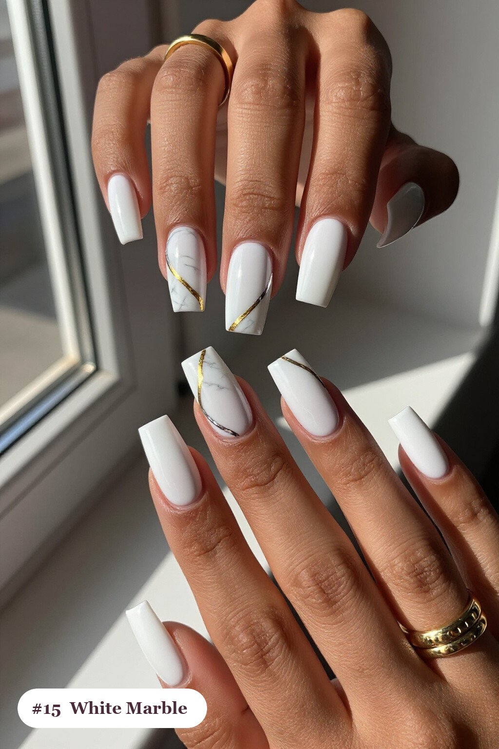 Long square white nails with bold marble veins in white and gold across every nail, with silver chrome details, perfect for winter - winter white nails