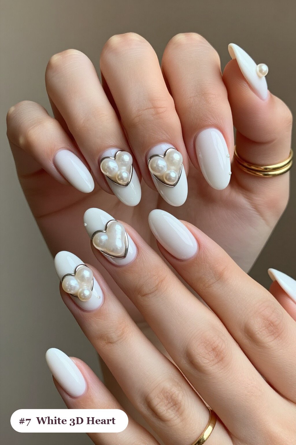 Medium almond white nails with chunky 3D gel hearts and pearls on three nails, with silver chrome details, perfect for winter - winter white nails